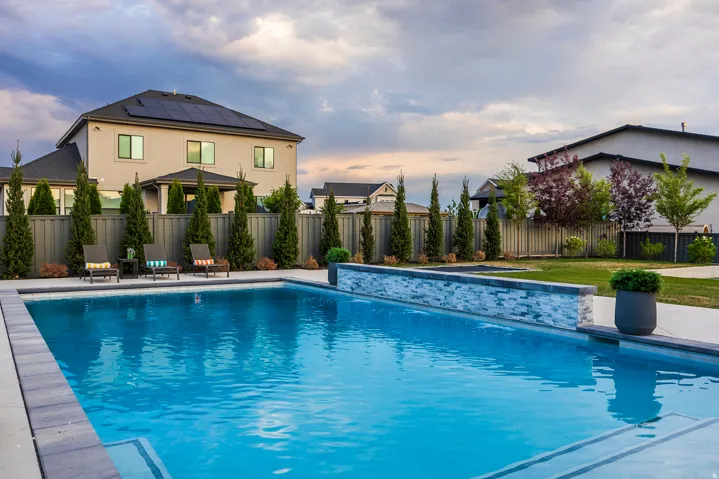 Spacious backyard featuring an in-ground swimming pool with integrated steps and a decorative stone-clad wall