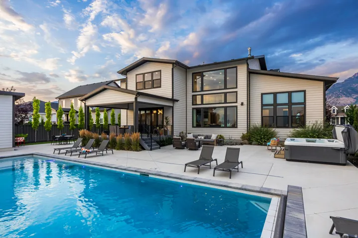 Expansive outdoor living area featuring a swimming pool, concrete patio, and covered porch
