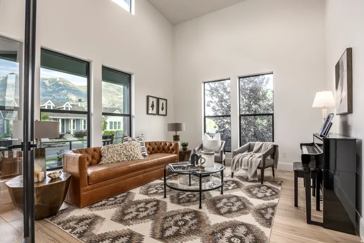 Living area with vaulted ceilings, light wood-finish flooring, and multiple large windows