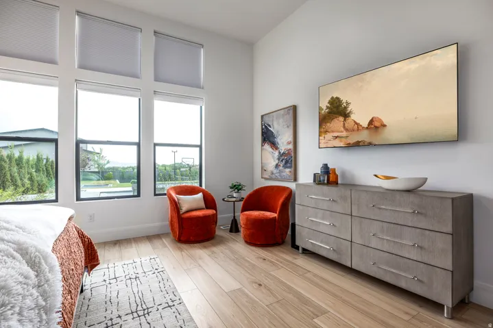 Room featuring tall windows with roller shades, wood-finish flooring, and a mounted display