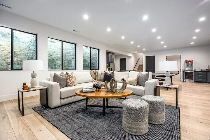 Spacious living area featuring light wood-finish flooring, recessed lighting, and large egress windows