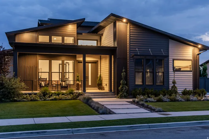 Contemporary architectural design featuring a prominent front porch, modern entry door, and a tiered roofline