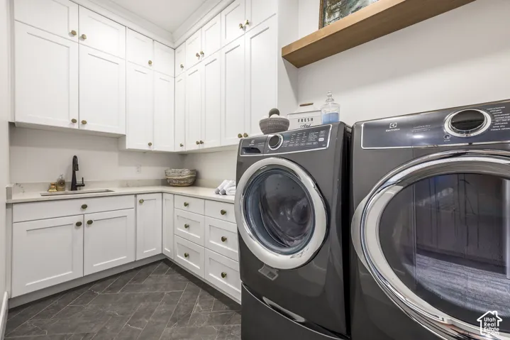 Laundry area featuring extensive white shaker cabinetry with brass hardware, light-toned countertop, and dark-toned diagonal tile flooring