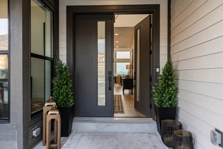 Modern entry door with vertical glass insert, dark trim, and light siding