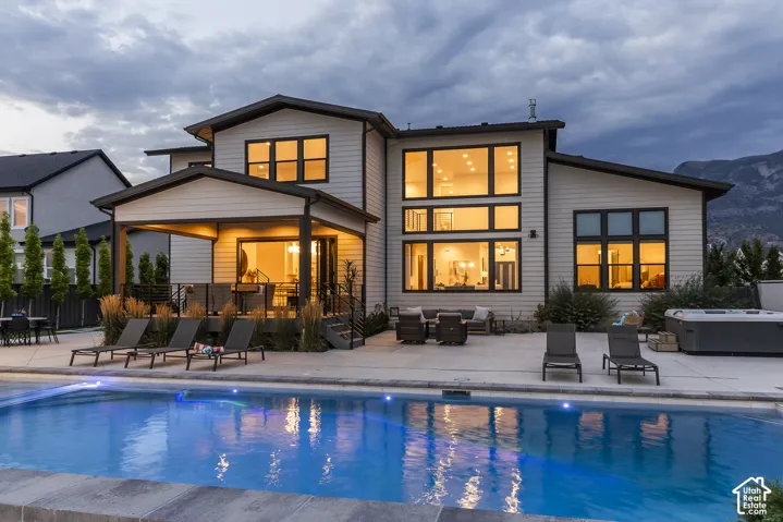 Contemporary residence featuring a private swimming pool with integrated lighting, an expansive concrete patio, and a covered outdoor living area