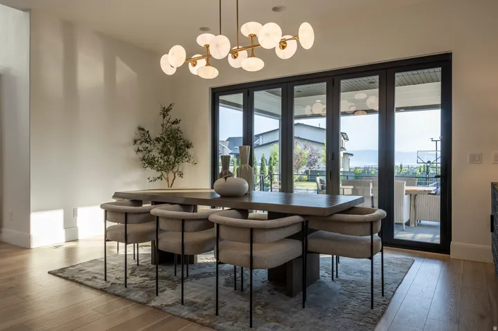Dining area featuring a contemporary chandelier, light wood-finish flooring, and expansive multi-panel glass doors opening to an exterior patio