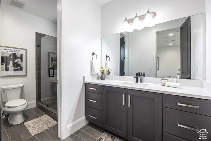 Contemporary bathroom featuring a spacious vanity with white countertop, dark wood-finish cabinetry, and an undermount sink with a black faucet