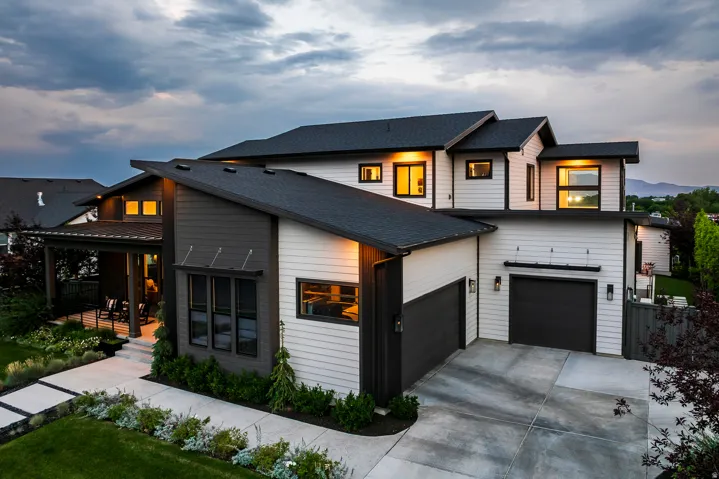 Contemporary architectural design featuring a multi-level structure with a dark shingle roof and contrasting white and dark gray siding