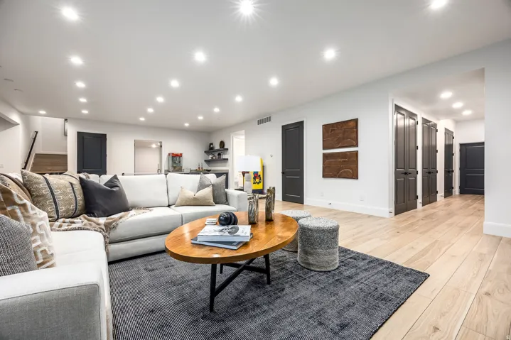 Spacious living area featuring light wood-finish flooring, recessed lighting, and white walls