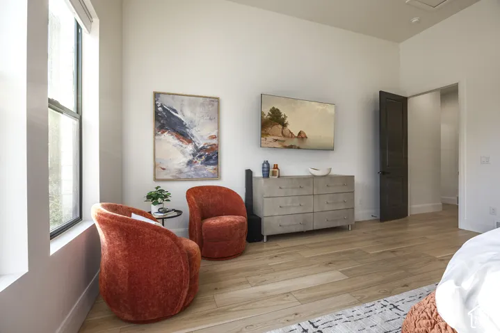 Bright interior space featuring light wood-finish flooring, tall ceilings, and a dark paneled door