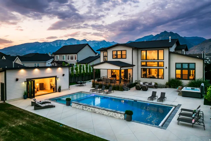 Contemporary exterior featuring a rectangular in-ground swimming pool, an outdoor spa, a detached accessory dwelling unit with bi-fold doors, and an expansive patio