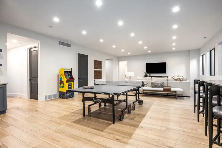 Spacious open-concept room featuring light wood-finish flooring, recessed lighting, and white walls