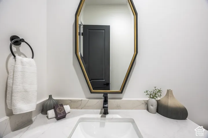 Geometric framed mirror with a gold accent, set above a white countertop featuring subtle veining