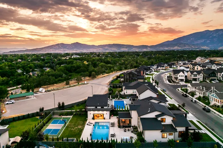 Modern residential community featuring a curved streetscape, mountain backdrop, and abundant green spaces
