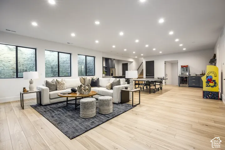 Spacious lower-level living area with light wood-finish flooring, recessed lighting, and multiple egress windows