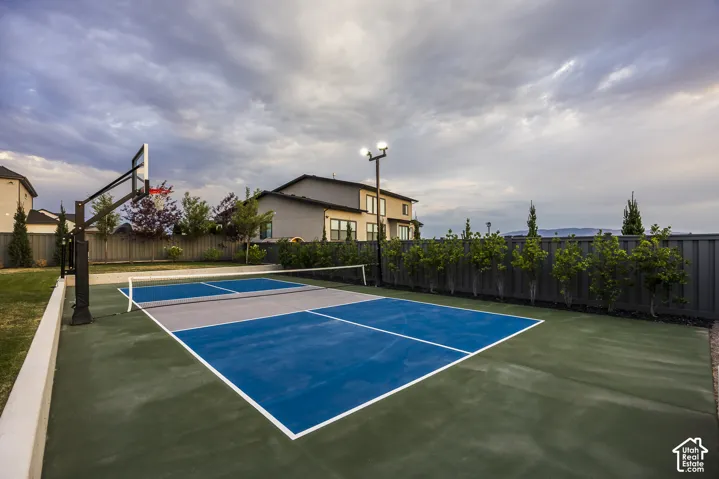 Outdoor multi-sport court featuring vibrant blue and grey playing surfaces, integrated lighting, and a basketball hoop