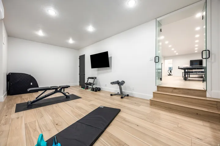 Spacious room featuring light wood-finish flooring, recessed lighting, and a wall-mounted flat-screen display