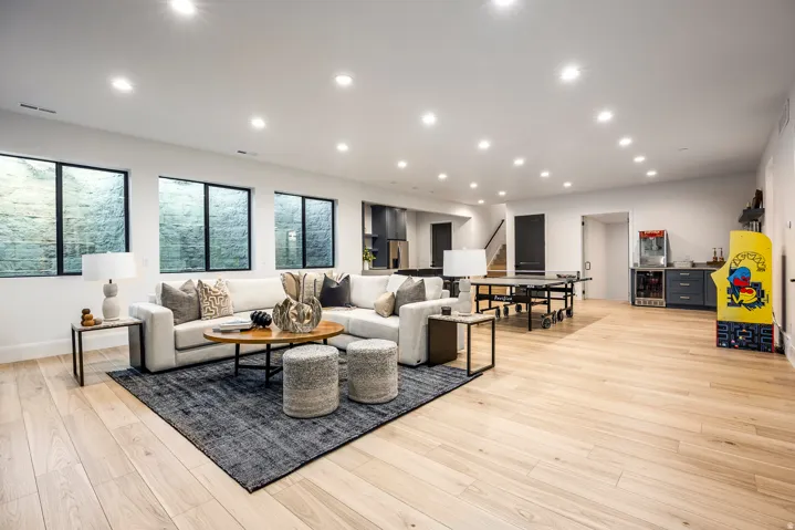 Spacious lower-level living area with light wood-finish flooring, recessed lighting, and multiple egress windows