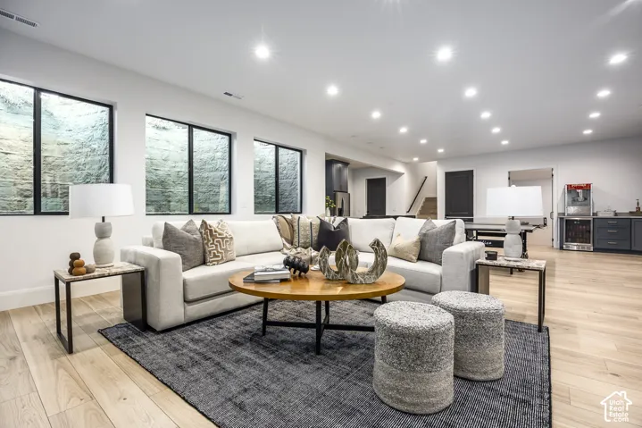 Spacious living area featuring light wood-finish flooring, recessed lighting, and large egress windows
