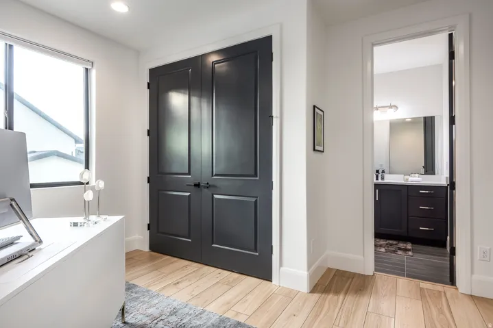 Double panel doors with matte black hardware, wood-finish flooring, and crisp white baseboards
