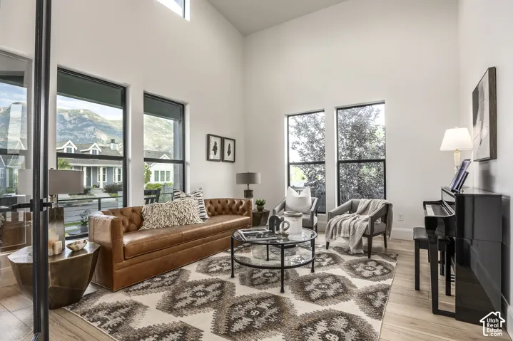 Living area with vaulted ceilings, light wood-finish flooring, and multiple large windows