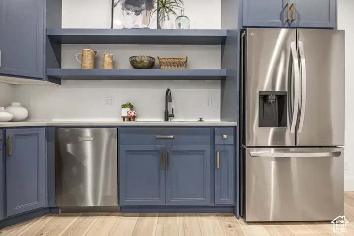 Integrated stainless steel refrigerator and dishwasher with blue shaker-style cabinetry
