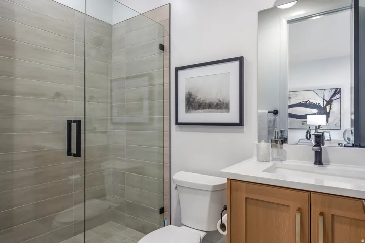 Glass-enclosed shower with horizontal tile surround and matte black hardware
