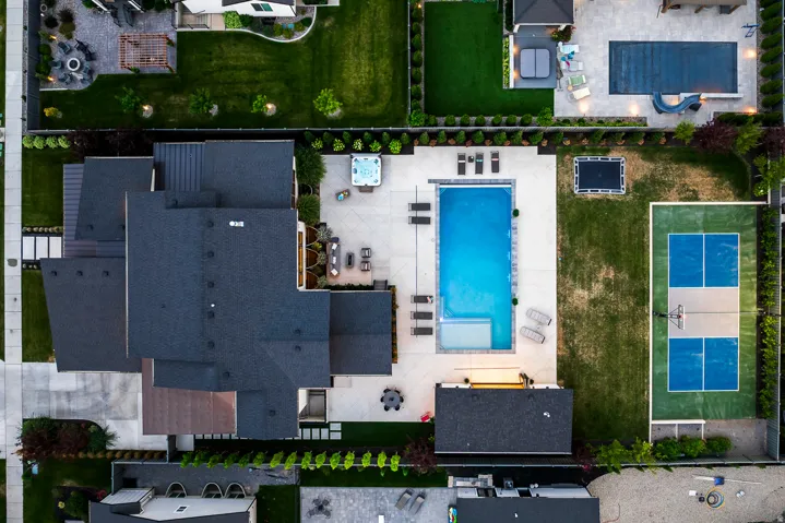 Expansive outdoor living area featuring a rectangular swimming pool, integrated spa, and adjacent hardscaping