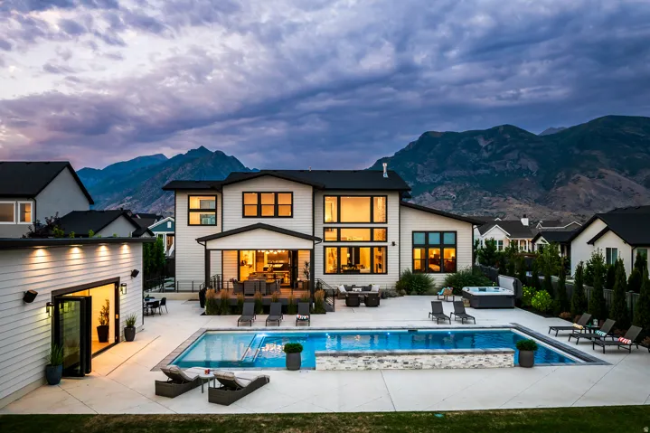 Contemporary residence featuring a spacious backyard, a large swimming pool with stone detailing, a separate spa, a multi-level deck for outdoor living, and a detached auxiliary building with bi-fold doors