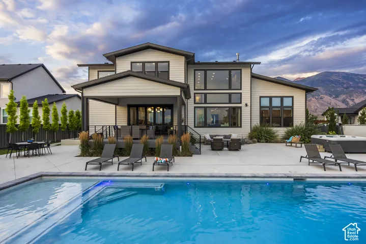 Contemporary rear facade with extensive patio space, a built-in swimming pool, and an integrated hot tub