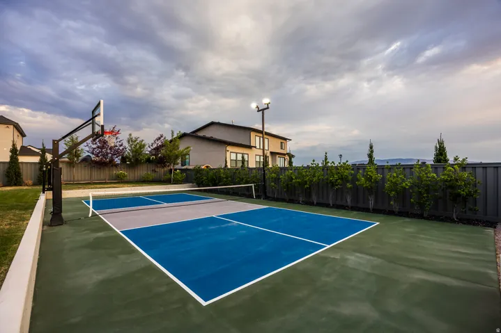 Outdoor multi-sport court featuring vibrant blue and grey playing surfaces, integrated lighting, and a basketball hoop