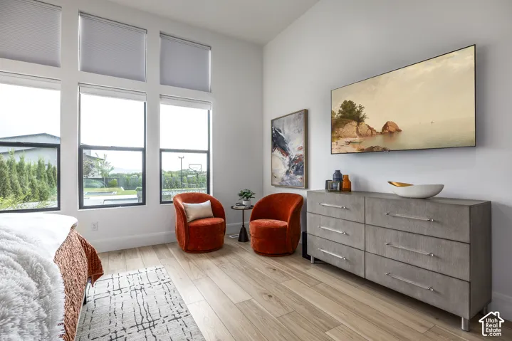 Room featuring tall windows with roller shades, wood-finish flooring, and a mounted display