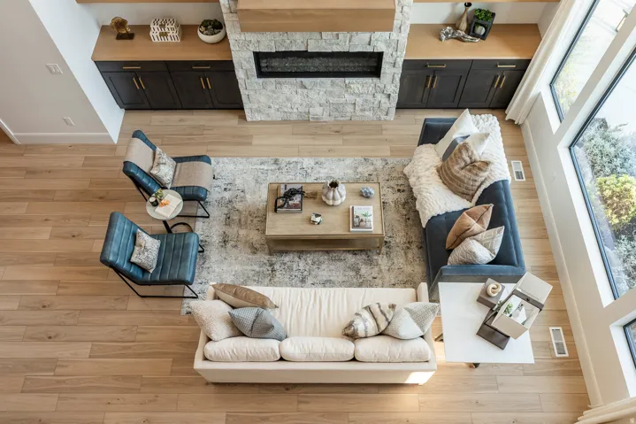 Spacious living area featuring light wood-finish flooring, a stone-clad fireplace with a hearth, and built-in cabinetry with a wood countertop