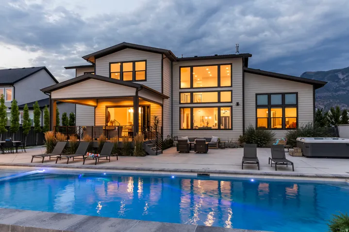 Contemporary residence featuring a private swimming pool with integrated lighting, an expansive concrete patio, and a covered outdoor living area