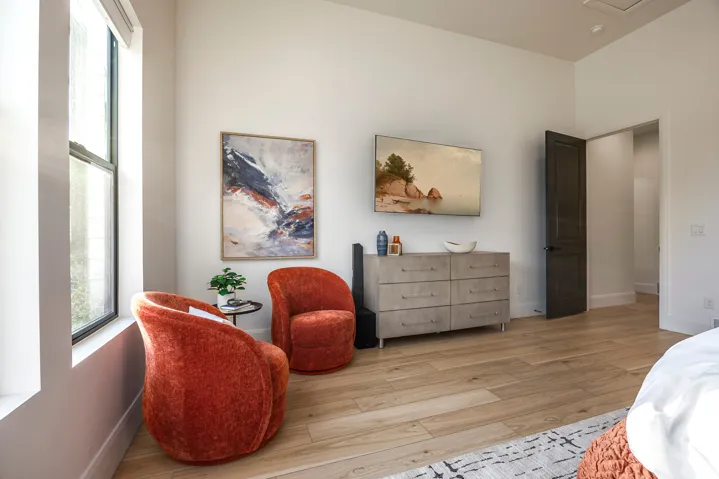 Bright interior space featuring light wood-finish flooring, tall ceilings, and a dark paneled door
