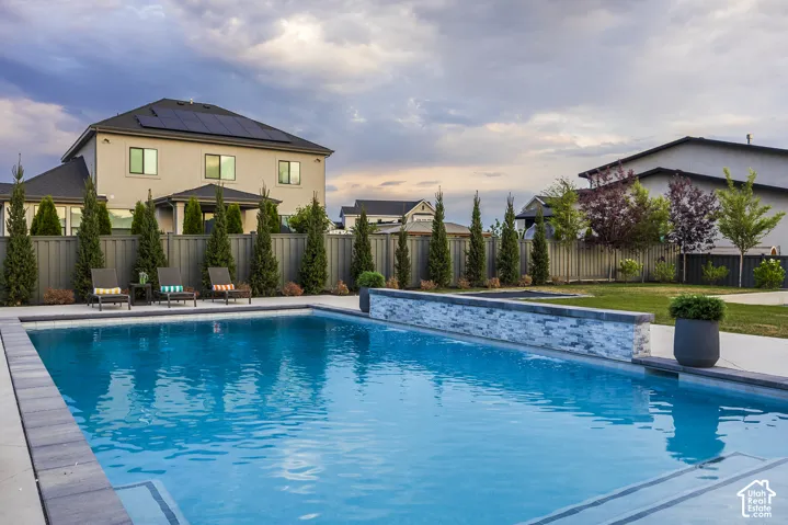 Spacious backyard featuring an in-ground swimming pool with integrated steps and a decorative stone-clad wall