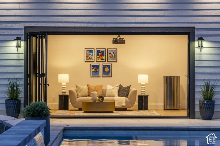 Outdoor entertaining space featuring bi-fold doors, a built-in projector, a beverage cooler, and exterior wall sconces