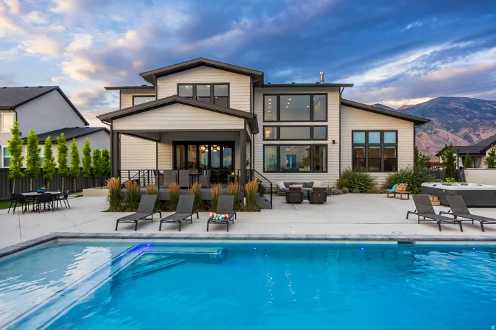 Contemporary rear facade with extensive patio space, a built-in swimming pool, and an integrated hot tub