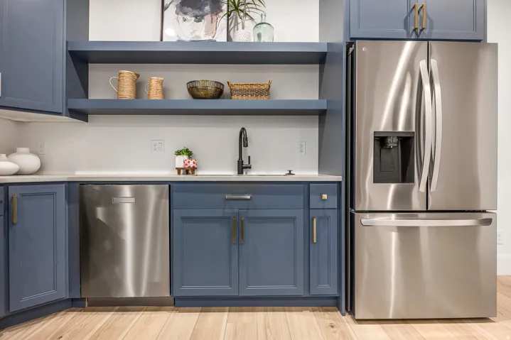 Integrated stainless steel refrigerator and dishwasher with blue shaker-style cabinetry