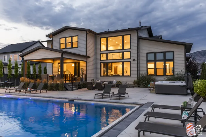 Modern multi-level residence featuring an inground swimming pool, expansive concrete patio, and a covered outdoor living area