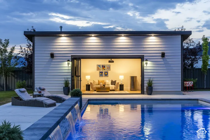 Modern pool house with wide-opening bi-fold doors, white horizontal siding, and a flat roofline