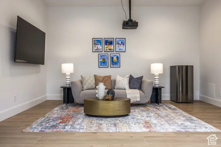 Entertainment space featuring light wood-finish flooring, white walls, and a recessed projector