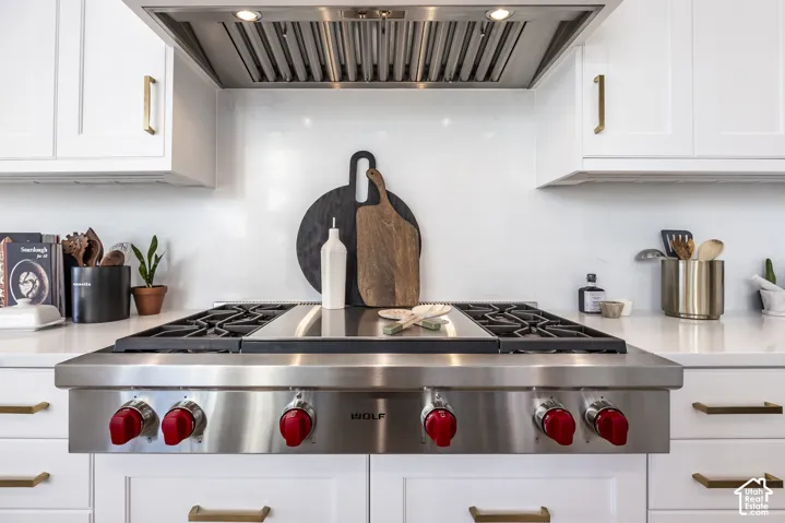 Stainless steel range with red control knobs, framed by white cabinetry with brass hardware