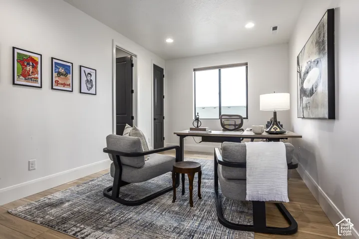 Bright room featuring wood-finish flooring, white walls, and a large window