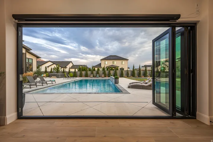 Expansive multi-panel folding glass doors opening to a large outdoor pool area