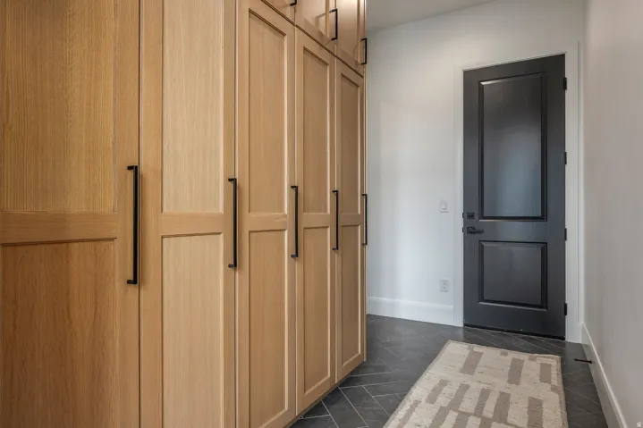 Custom built-in wood cabinetry with matte black hardware, complementing the dark-paneled interior door