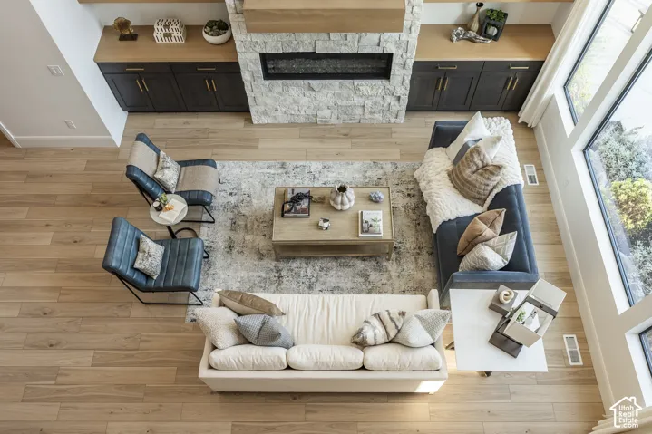 Spacious living area featuring light wood-finish flooring, a stone-clad fireplace with a hearth, and built-in cabinetry with a wood countertop