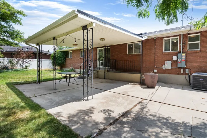 Expansive concrete patio area featuring a covered pergola with decorative metal supports