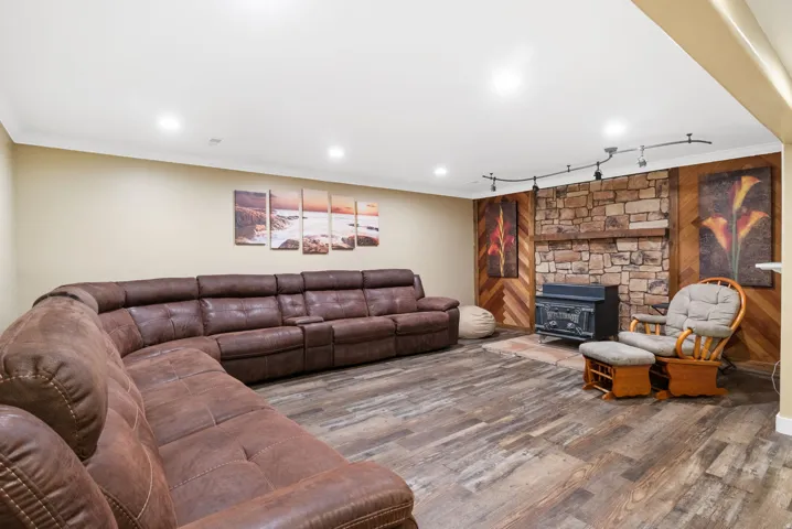 Finished room featuring wood-finish flooring, recessed lighting, and a stone-faced fireplace with a wood mantle