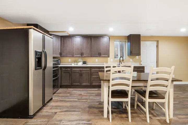 Kitchen area featuring wood-finish flooring, dark wood cabinetry, light countertops, and a stainless steel refrigerator
